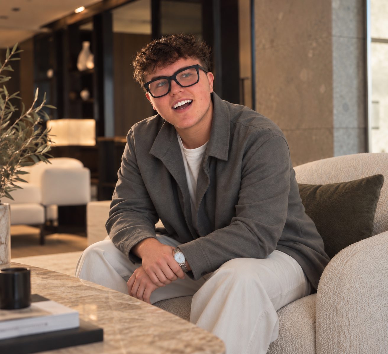 Jarvis laughing on a lounge in a light-filled room